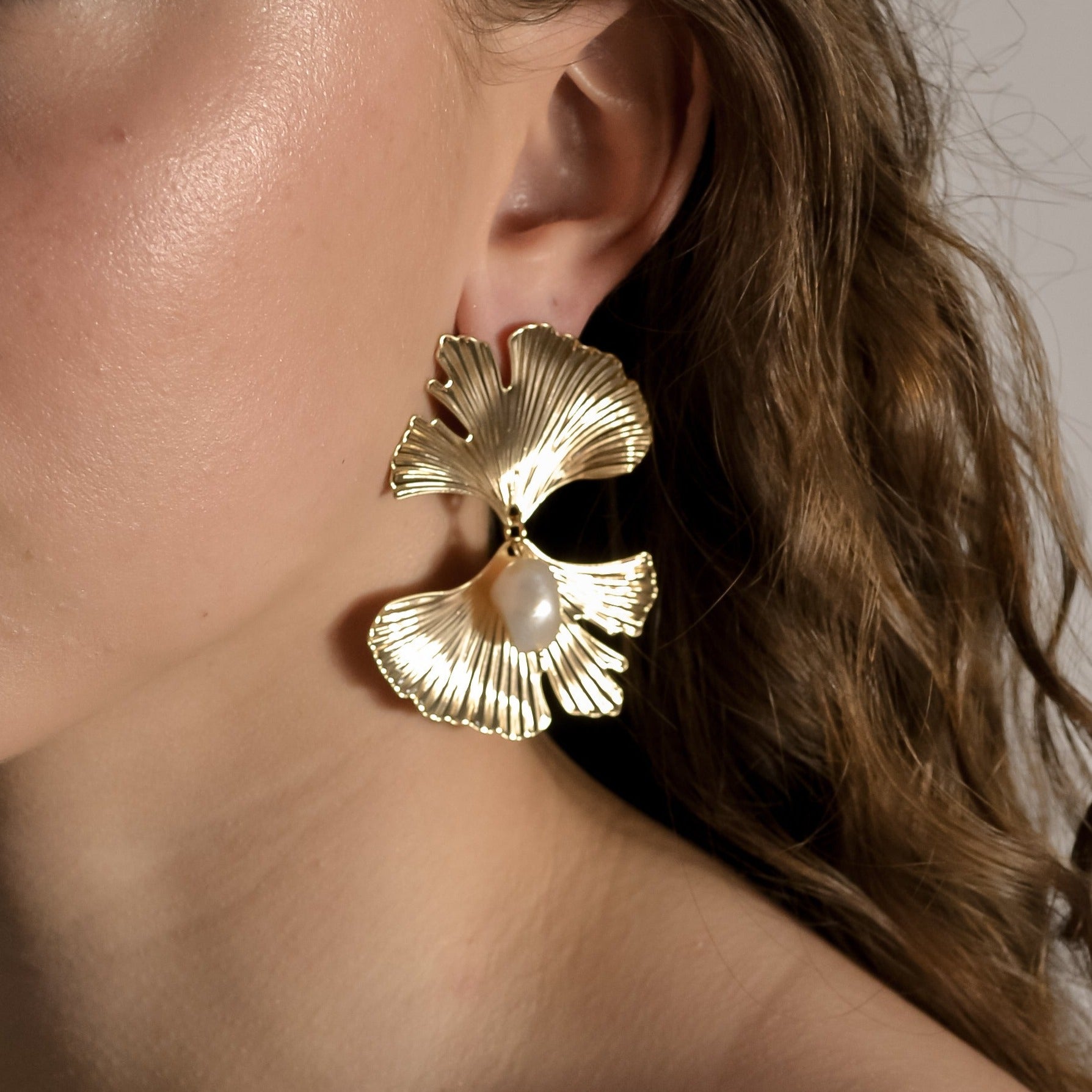 model wearing Melody collection, large gold fan with stud and single  seed pearl earrings 