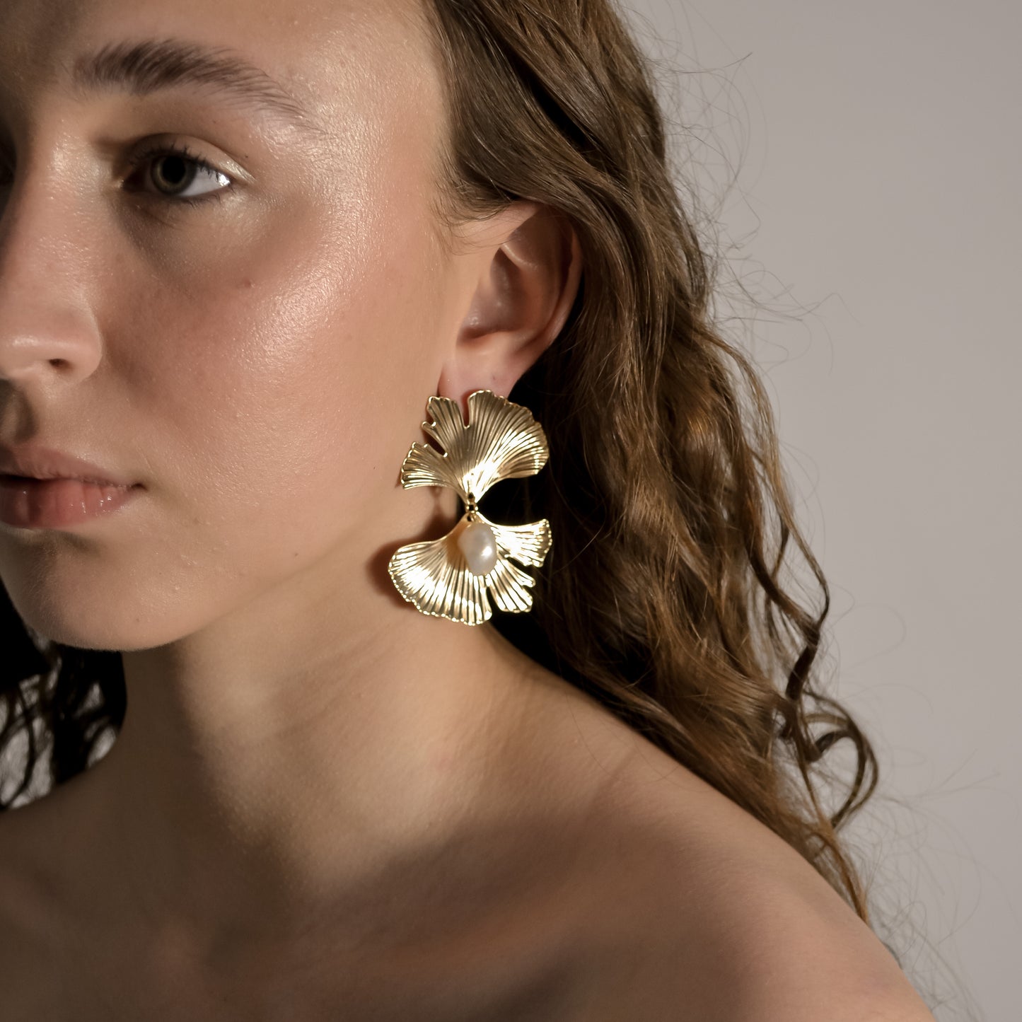 model wearing Melody collection, large gold fan with stud and single  seed pearl earrings 